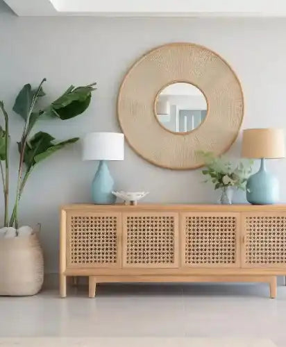 Wooden cabinet with woven design, round wicker mirror, and decorative items in a room.